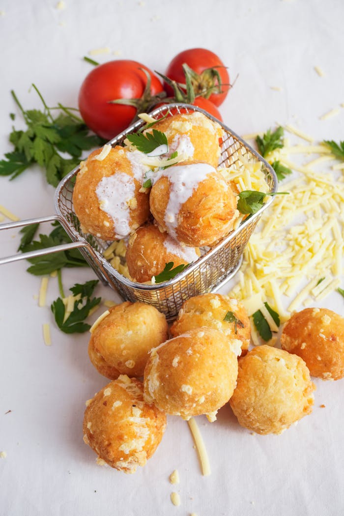 Delicious crispy cheese balls garnished with fresh tomatoes and parsley on a white background.